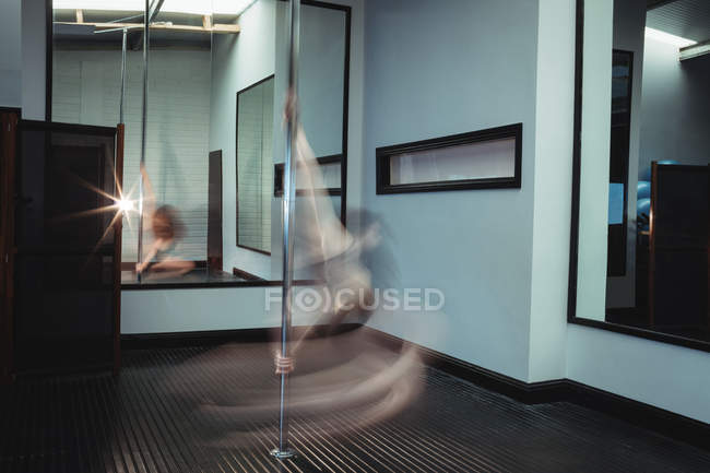 Danseuse de pôle pratiquant la pole dance dans un studio de fitness — Photo de stock