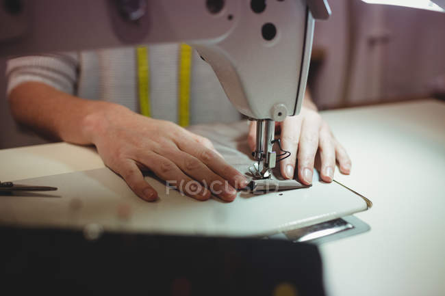 Immagine ritagliata di sarta donna che cuce sulla macchina da cucire in studio — Foto stock
