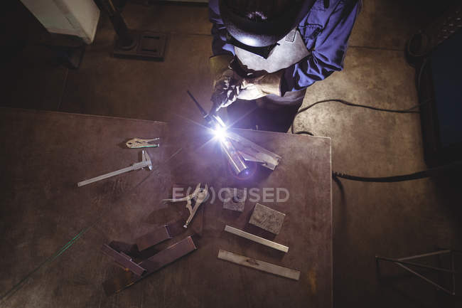 High angle view of Female welder working on piece of metal in workshop — Stock Photo