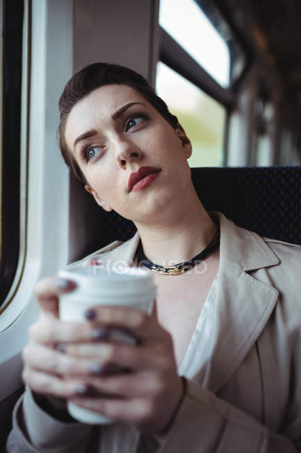 Задумчивая женщина сидит у окна в поезде — стоковое фото