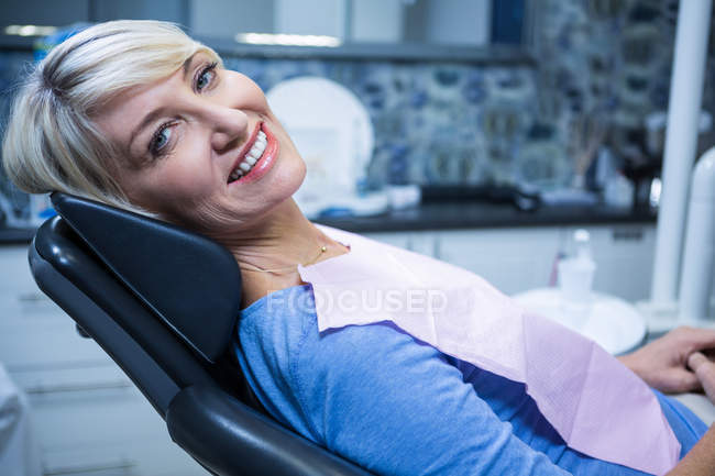 Paciente sonriente sentado en la silla del dentista en la clínica - foto de stock
