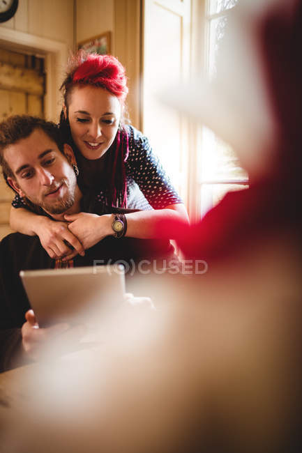 Feliz pareja hipster usando tableta digital en casa - foto de stock