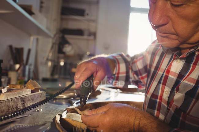 Aufmerksame Goldschmiedin mit Handstückmaschine in Werkstatt — Stockfoto