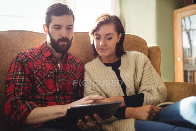 Couple using digital tablet in living room at home — Stock Photo