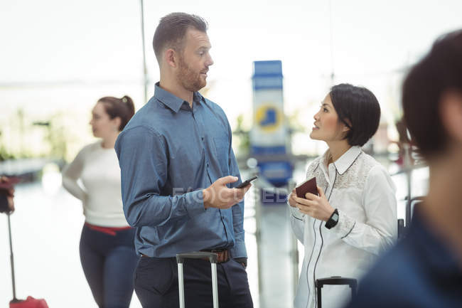 Gente de negocios con tarjeta de embarque y teléfono móvil en la terminal del aeropuerto - foto de stock