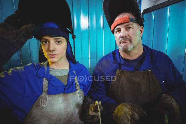 Retrato de soldador macho e fêmea em pé juntos na oficina — Fotografia de Stock