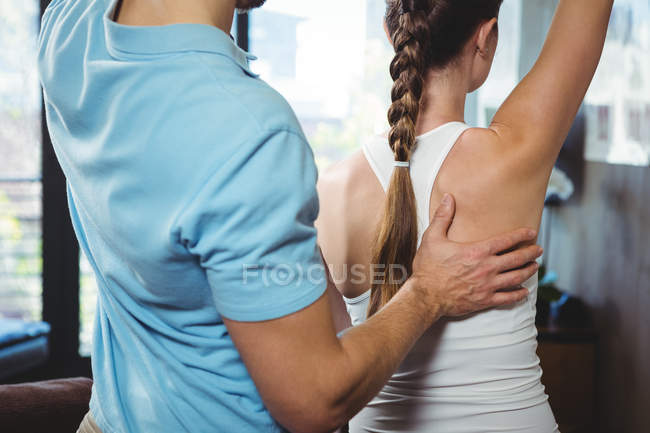 Fisioterapeuta corrigiendo la posición de la paciente femenina en la clínica - foto de stock