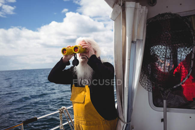 Pescador mirando a través de binoculares desde el barco - foto de stock
