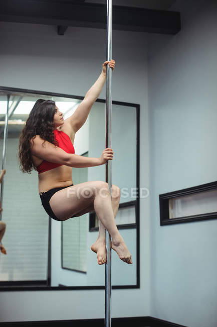 Atraente Pole dançarina praticando pole dance no estúdio de fitness — Fotografia de Stock