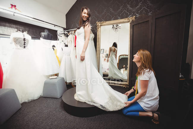 Жінка намагається на весільній сукні в студії за допомогою креативного дизайнера — стокове фото