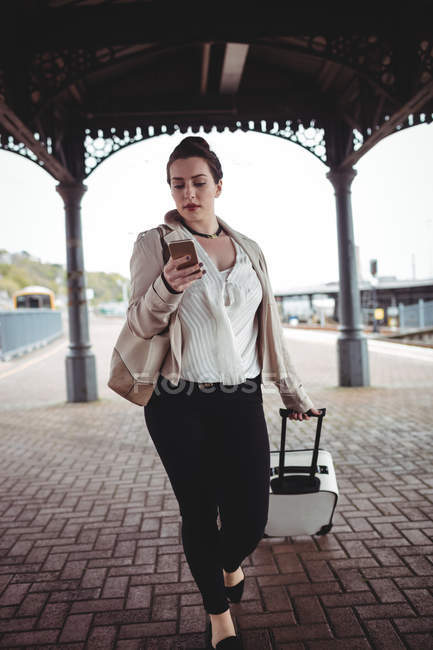 Молодая женщина с помощью мобильного телефона на железнодорожной станции платформы — стоковое фото