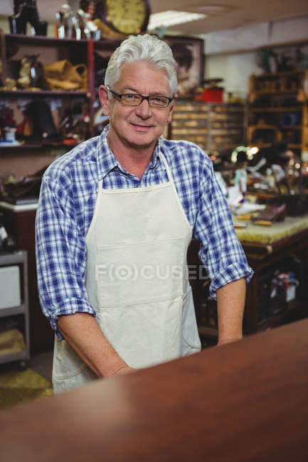 Selbstbewusst lächelnder Schuhmacher steht in Werkstatt — Stockfoto