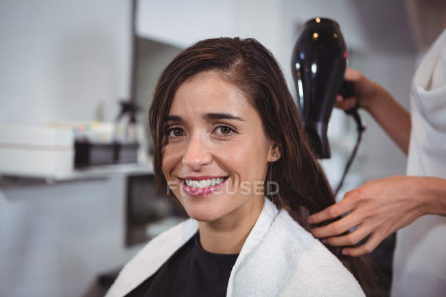 Porträt einer Frau, die sich im Friseursalon die Haare mit einem Föhn trocknen lässt — Stockfoto