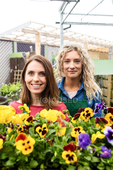 Портрет двух женщин-флористок, улыбающихся в центре сада — стоковое фото