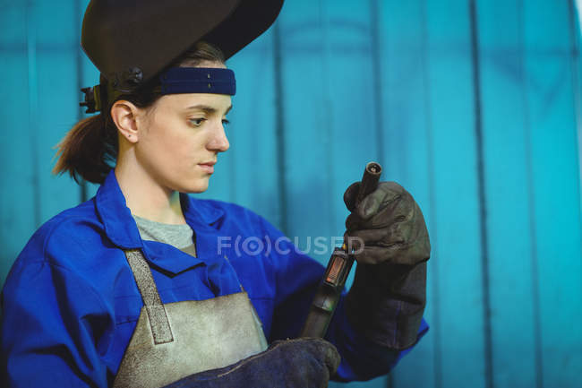 Soldador fêmea examinando tocha de soldagem na oficina — Fotografia de Stock
