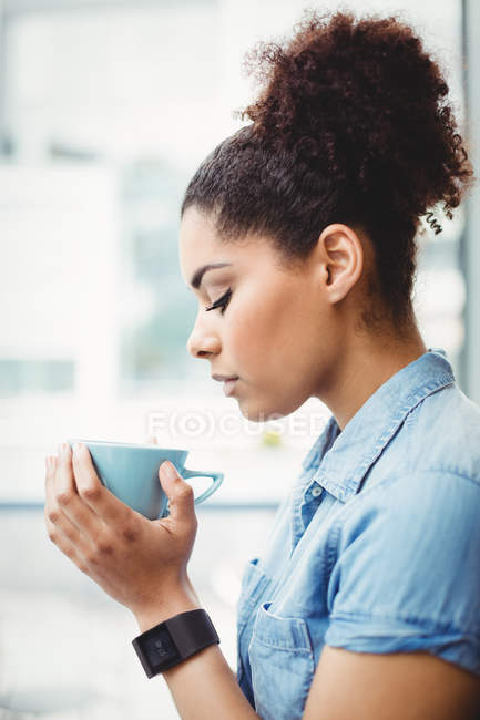 Vue latérale de la femme avec les yeux fermés tout en tenant une tasse de café au restaurant — Photo de stock
