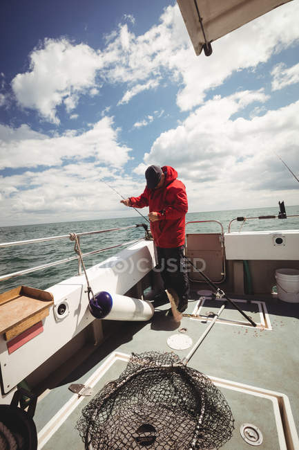 Рыбак рыбалка с удочкой с лодки — стоковое фото