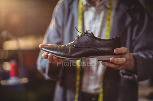 Sezione centrale del calzolaio che esamina una scarpa in officina — Foto stock