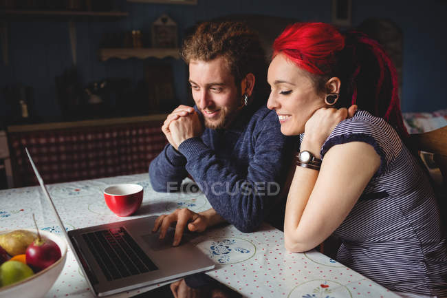 Усміхнена пара хіпстерів використовує ноутбук вдома — стокове фото