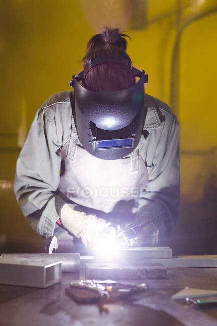 Soudeuse travaillant sur un morceau de métal en atelier — Photo de stock