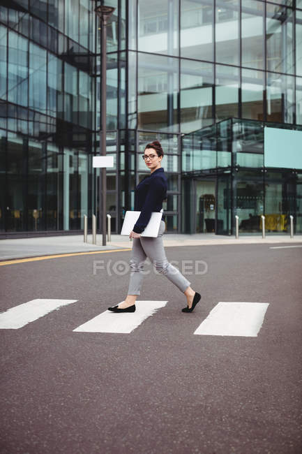 Full length portrait of businesswoman walking by office building on road — Stock Photo