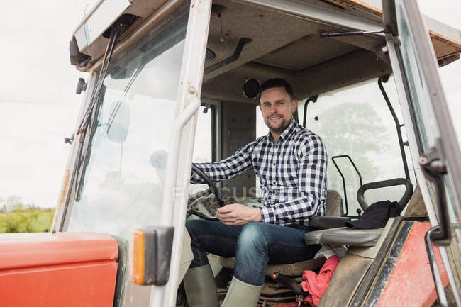 Портрет счастливого фермера за рулем трактора — стоковое фото