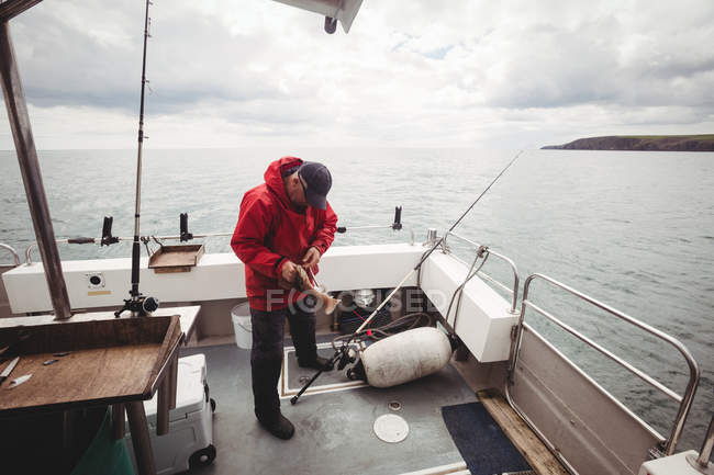 Middle aged Fisherman holding fish on boat — Stock Photo