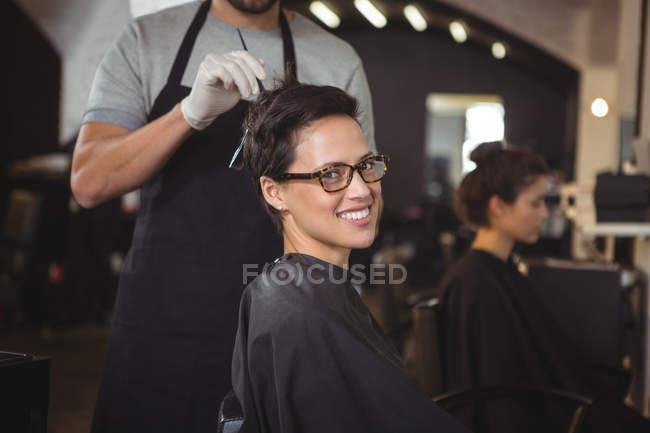 Hairdresser dyeing hair of client at salon — Stock Photo