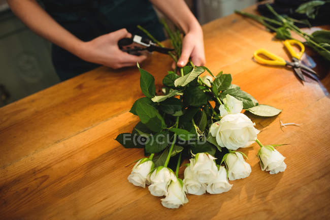 Обрезанное изображение женщины-флористки, обрезающей стебли цветов в цветочном магазине — стоковое фото