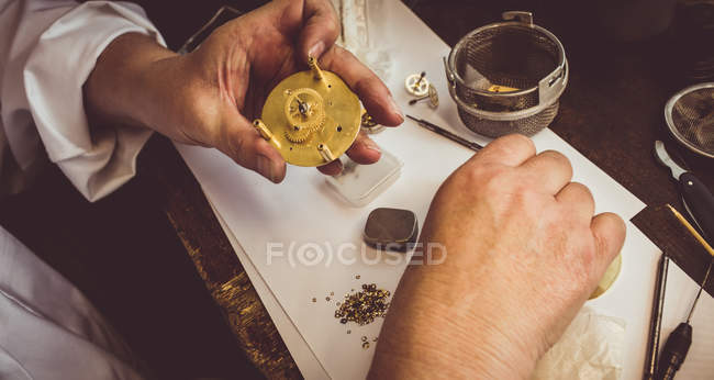 Mains d'horloger réparer une montre dans l'atelier — Photo de stock