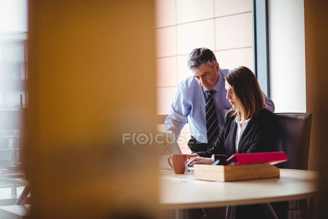 Бизнесмен обсуждает с коллегой за ноутбуком в офисе — стоковое фото