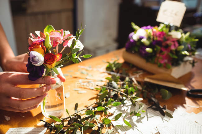 Крупним планом жіночий флорист організовує квіти в пляшці в її квітковому магазині — стокове фото