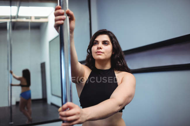 Attractive Pole dancer practicing pole dance in fitness studio — Stock Photo