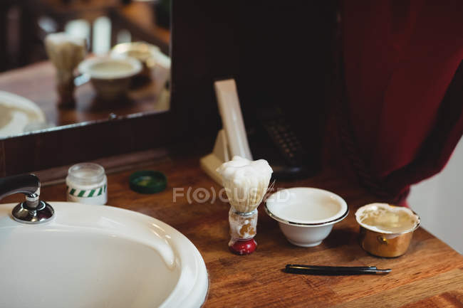 Waschbecken, Rasierpinsel, Rasiermesser und Schale auf Holztisch im Friseursalon — Stockfoto