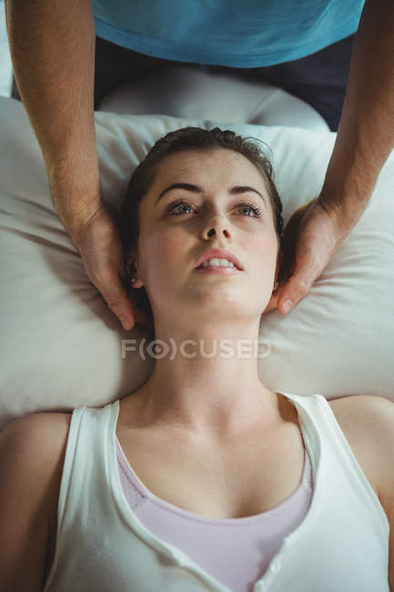 Male physiotherapist giving head massage to female patient in clinic — Stock Photo