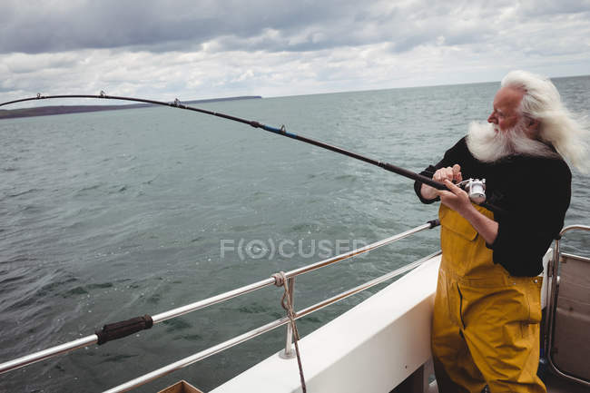 Pescatore pesca con canna da pesca dalla barca — Foto stock