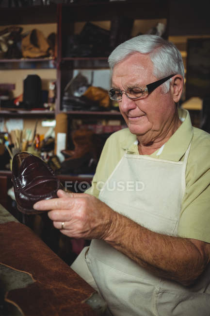Calzolaio esaminando una scarpa in officina — Foto stock