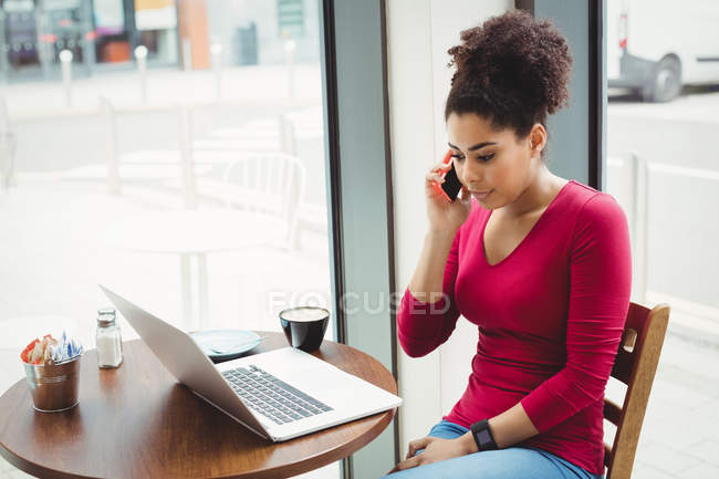 Young woman talking on phone while sitting at restaurant — Stock Photo
