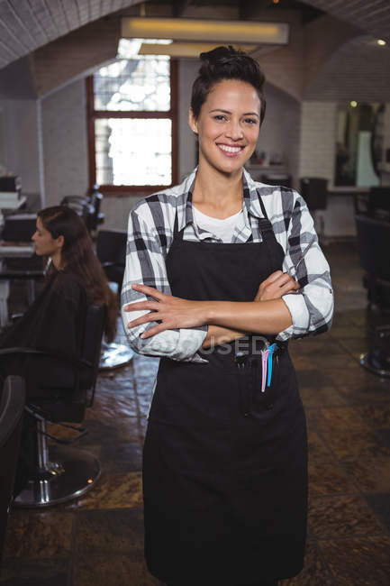 Портрет женщины-парикмахера, стоящей со скрещенными руками в салоне — стоковое фото