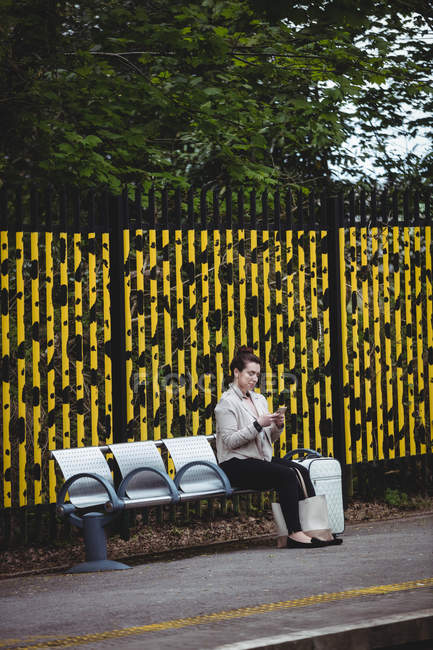 Jovem mulher sentada no banco na plataforma da estação ferroviária — Fotografia de Stock