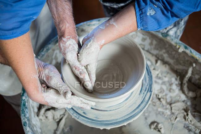 Potier masculin de section moyenne aidant potier féminin dans l'atelier de poterie — Photo de stock