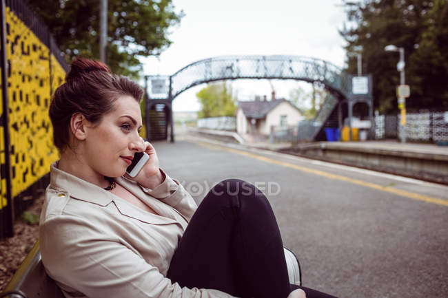 Beautiful woman talking on phone at railroad station — Stock Photo