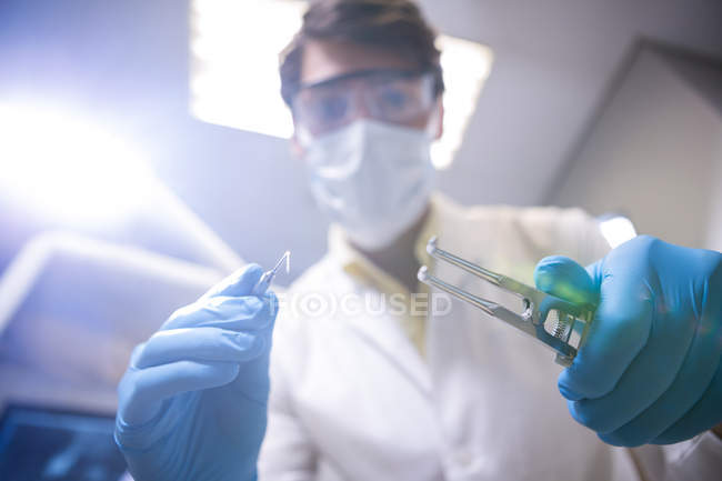 Low angle view of Dentist in surgical mask holding dental tools in dental clinic — Stock Photo