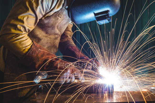 Saldatore maschio che lavora su un pezzo di metallo in officina — Foto stock