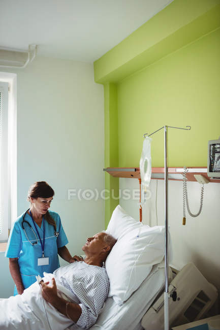 Enfermeira consolando paciente idoso no hospital — Fotografia de Stock