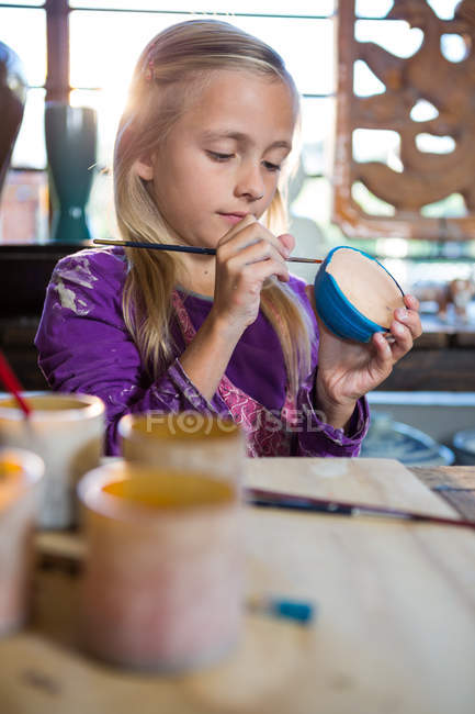Attentive girl painting on bowl in pottery workshop — Stock Photo