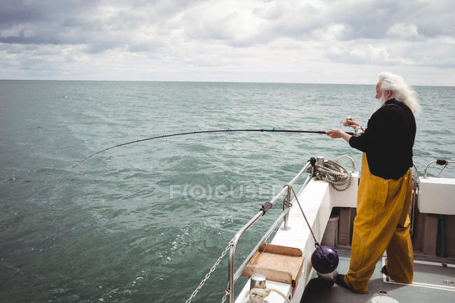 Fisherman fishing with fishing rod from boat — Stock Photo