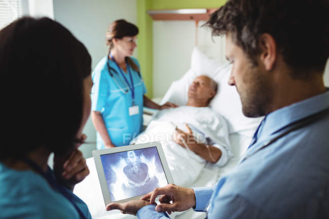 Médico y enfermera varones mirando tableta digital en el hospital - foto de stock
