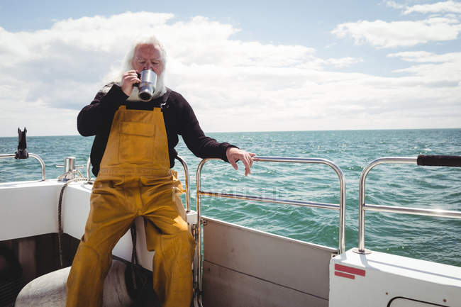 Fisherman drinking coffee from cup on boat — Stock Photo