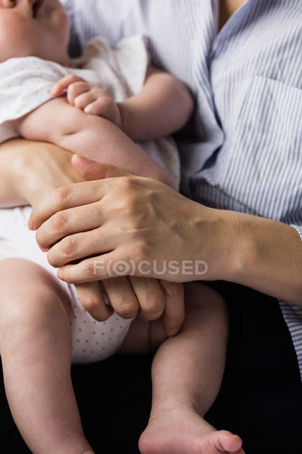 Abgeschnittenes Bild einer Mutter, die ihr Baby zu Hause trägt — Stockfoto
